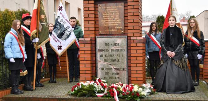 uczniowie stoją przy pomniku